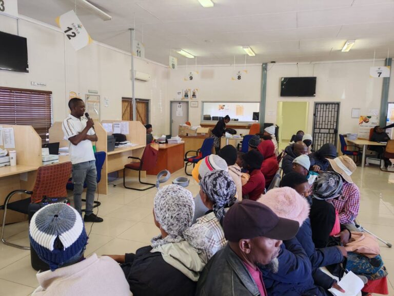 People at a SASSA office seated in a queue while a staff member explains the July 2025 grant application process, SASSA Grant Applications Open for July 2025